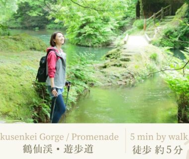 Traveler standing on mossy streamside path at Kakusenkei Gorge with lush green forest near Shirasagiyu Tawaraya, Ishikawa