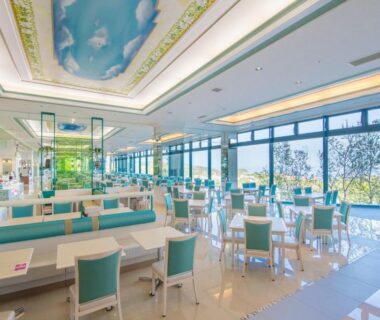 Spacious dining room with turquoise chairs, booths, large windows and painted sky ceiling at Shiretoko Daiichi Hotel