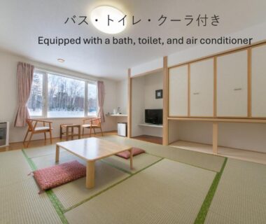 Tatami mats, low table and cushions in a bright Shiretoko Village guest room with snowy tree view in Hokkaidō