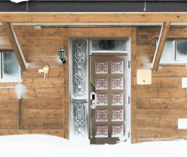 Wooden entrance with ornate metal door, frosted windows and snow at base, Shiretoko Village Hokkaidō