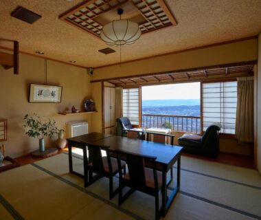 Traditional tatami room with low table, shoji screens and window seating overlooking distant hills at Shiroyama Ryokan, Nara