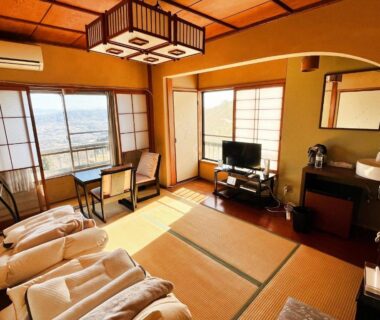 Traditional tatami room with folded futons, shoji screens, low table and window seating at Shiroyama Ryokan in Nara