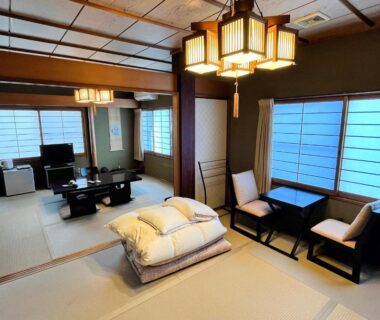 Tatami room with folded futons, shoji screens and seating at Shiroyama Ryokan in Nara, Kansai