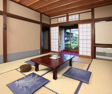 Tatami room with low table, zabuton cushions and shoji doors opening to a garden at Shitanda, Gifu, Chūbu