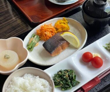 Tray with rice bowl, grilled fish, miso soup, pickled vegetables and cups on lacquered tray