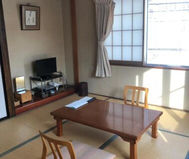 Traditional tatami room with low table, floor cushions, shoji window and TV at Shiunso in Tochigi