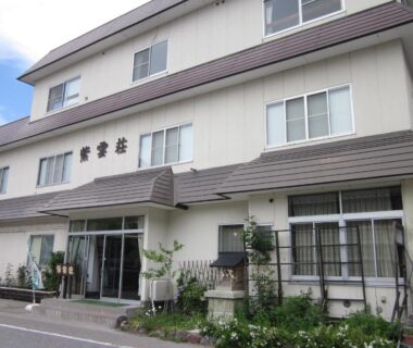 Multi-story ryokan facade with glass entrance, potted plants, signage and windows at Shiunso in Tochigi, Kanto