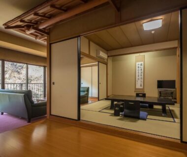 Tatami room with low table and sofa by balcony at Shiunso in Kanagawa