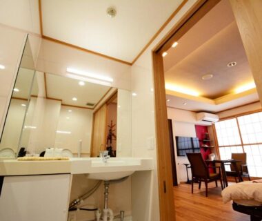 Sink and vanity opening into airy guest room with shoji screens, low dining table and bedding at Shizukatei Iwate Japan