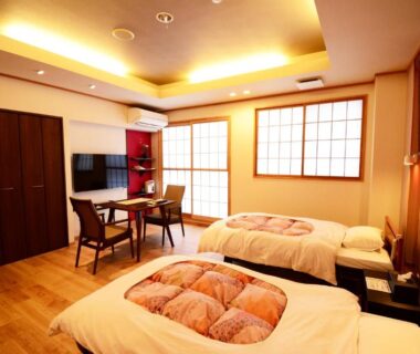 Room with futon bedding, shoji screens, low table, TV and wooden floor at Shizukatei in Iwate