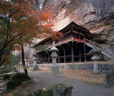 Wooden cliffside pavilion with stone lanterns, autumn foliage and stone path at Shizukatei, Iwate