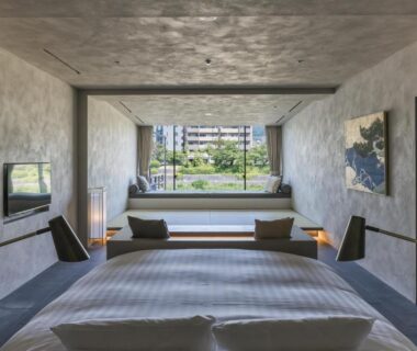 Low platform bed and window bench overlooking greenery and city buildings at Shizuru 鴨川, Kyoto