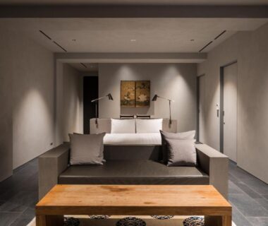 Minimalist guest room with bed, sofa, wooden bench and soft ambient lighting