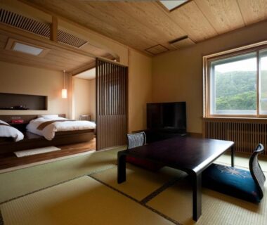 Tatami-floored room with low table and beds at Shogetsu Grand Hotel in Hokkaido, Japan