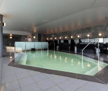 Spacious indoor onsen with tiled deck, handrails and washing stations at Shogetsu Grand Hotel Hokkaidō