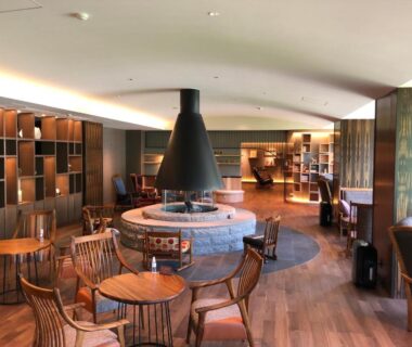 Central fireplace lounge with wooden chairs at Shogetsu Grand Hotel in Hokkaidō, Japan