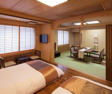 Twin beds with adjoining tatami seating and low table, shoji screens and warm wood interior at Shogetsu Grand Hotel Hokkaidō
