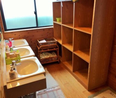 Three sinks with mirrors, wooden shelving and wicker baskets in Shokinkan wash area, Kumamoto