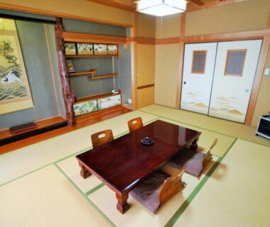 Traditional tatami room with low table, zabuton seating, tokonoma alcove and fusuma doors at Shokinkan in Kumamoto