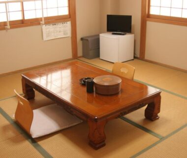 Japanese tatami room with low lacquered table, floor chairs, shoji screens, small TV and compact refrigerator