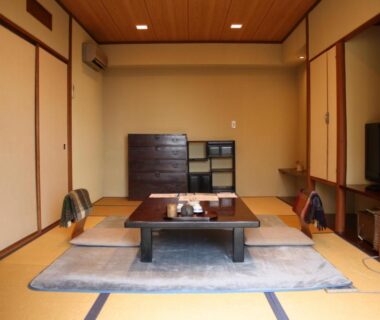 Traditional tatami room with low table, cushions, shoji doors and wooden storage at Shorenkan Yoshinoya, Kyoto