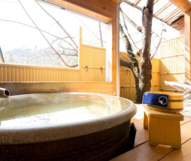 Round onsen tub on wooden deck with tree, Shosenkaku, Nagano, Chūbu, Japan