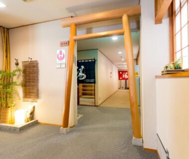 Carpeted ryokan corridor with torii-style wooden frame and noren curtains at Shosenkaku in Nagano