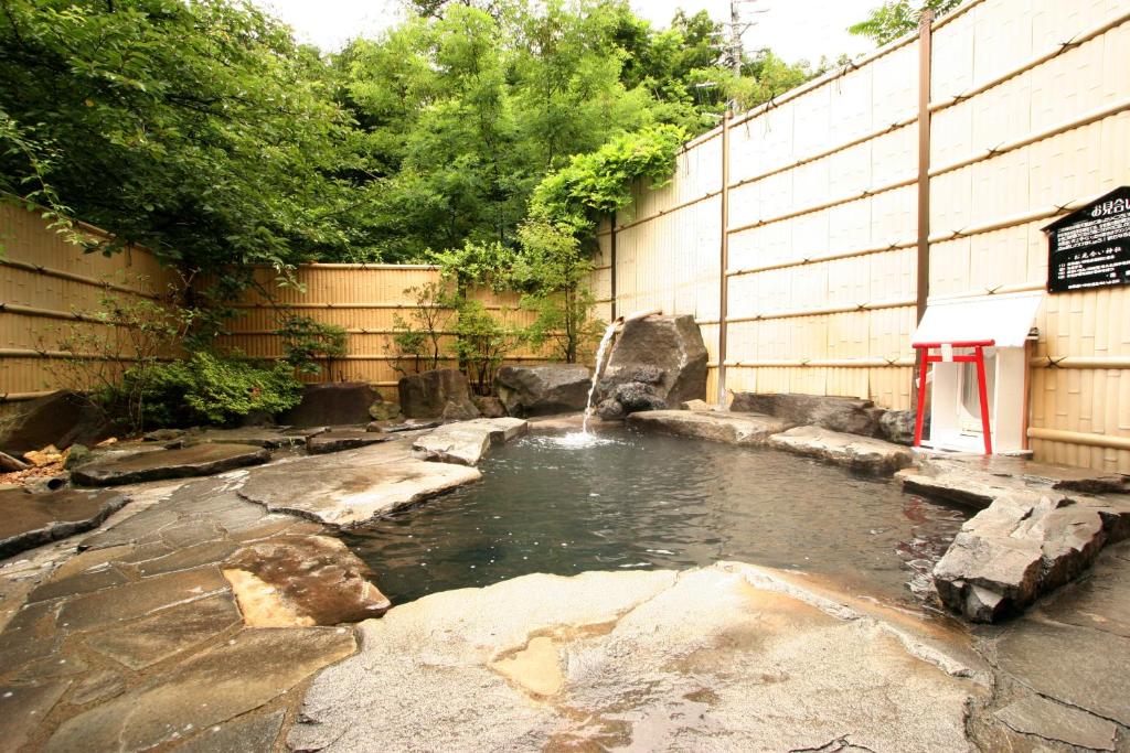 Stone Outdoor Onsen Shosenkaku Nagano Rock-lined outdoor onsen bath with wooden fence and lush greenery at Shosenkaku in Nagano
