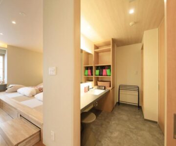 Bright wood interior with raised tatami platform, twin beds, vanity sink, and shoji window at Shouhakutei Azumaso