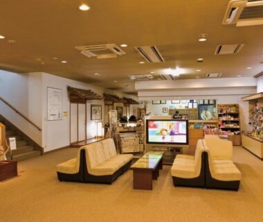 Lobby with low sofa seating, television, reception desk and guest lockers at Shugyoku no Yu Yakushido Onsen in Iwate