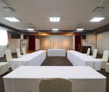 U-shaped meeting room with covered chairs and stage at Shugyoku no Yu Yakushido Onsen in Iwate