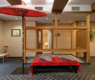 Lobby seating area with shoji screens, red umbrella and low bench at Shuzenji Onsen Hotel Takitei in Shizuoka