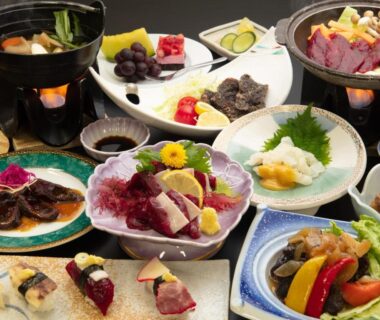 Assorted traditional Japanese dishes including sashimi, grilled items, vegetables and small hot pots on a banquet table