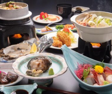 Multi-course Japanese meal with sashimi, simmering hot pots and assorted side dishes on a low table