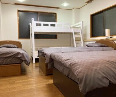 Room with two single beds and white bunk bed on hardwood floor at Sky Tree INN II Tokyo