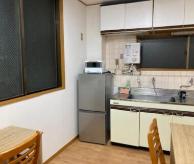 Compact kitchenette with fridge, microwave, sink and wooden dining table at Sky Tree INN Ⅱ Tokyo