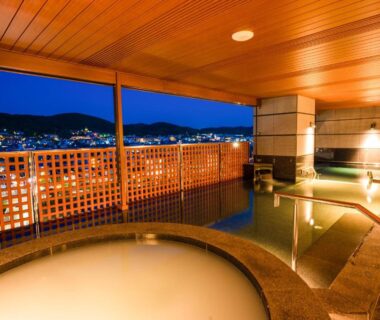 Outdoor stone baths on wooden terrace at Sora Niwa Terrace Kyoto Bettei overlooking Kyoto city lights