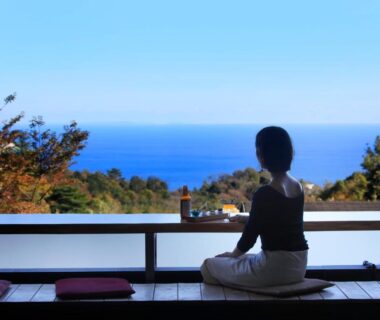 Person seated at low ledge overlooking ocean at Soratoniwa Atami Izusan Shizuoka