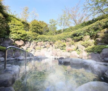Steaming rock-lined outdoor onsen surrounded by greenery at Soratoniwa Atami Izusan, Shizuoka