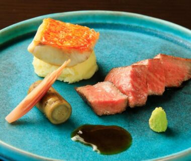 Seared meat slices with sauce and vegetable garnish on blue plate
