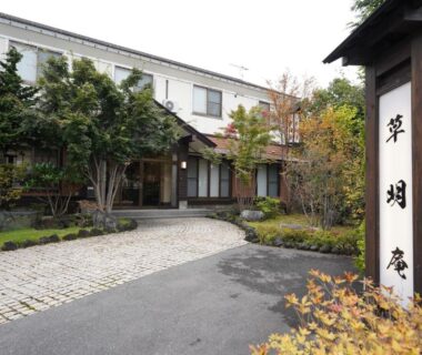 Traditional ryokan entrance with stone driveway, landscaped shrubs and wooden sign at Soumeian, Gunma, Kantō