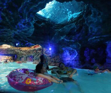 Guests floating on inner tubes in illuminated indoor grotto pool at Spa Resort Hawaiians, Fukushima