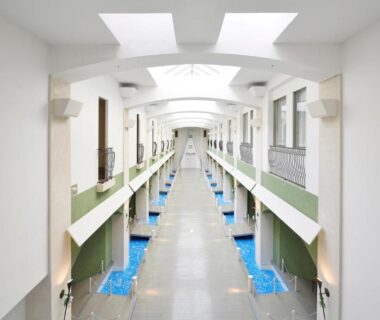 Long skylit atrium corridor with blue water features, Spa Resort Hawaiians VIR Port, Fukushima Tōhoku