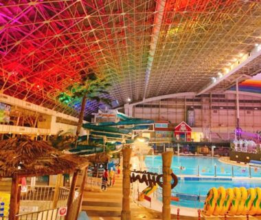 Bright indoor tropical pool complex with water slides, palm trees and large vaulted ceiling at Spa Resort Hawaiians in Fukushima