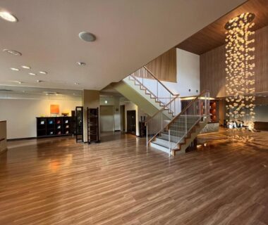 Spacious wooden-floored lobby with modern staircase and hanging light installation at Suichokan in Hokkaidō