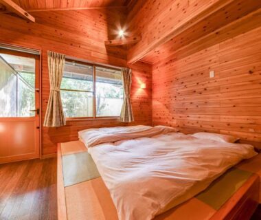 Bright wood-paneled guest room with futon on tatami beside window at Spa & Resort Kujukuri Taiyou-no-sato, Chiba Kantō