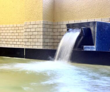 Water pouring from a spout into a tiled indoor onsen bath at Sports Plaza Shiki Haradaso Niigata