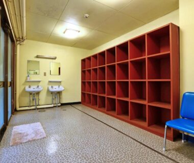 Changing room with wooden cubbies, sinks and chair at Sports Plaza Shiki Haradaso, Niigata