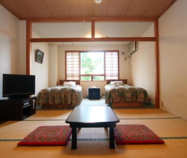Tatami room with low table, cushions and twin beds by shoji window at Star Hotel Akakura, Niigata