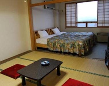 Tatami-floored room with two Western beds, low table and shoji window at Star Hotel Akakura in Niigata